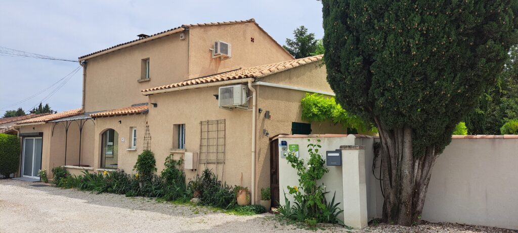 Vue de la façade nord de L’Oustau dei Aucèus, petit mazet mitoyen au mas des propriétaires, avec le grand cyprès marquant l’entrée du gîte à Saint-Rémy-de-Provence.