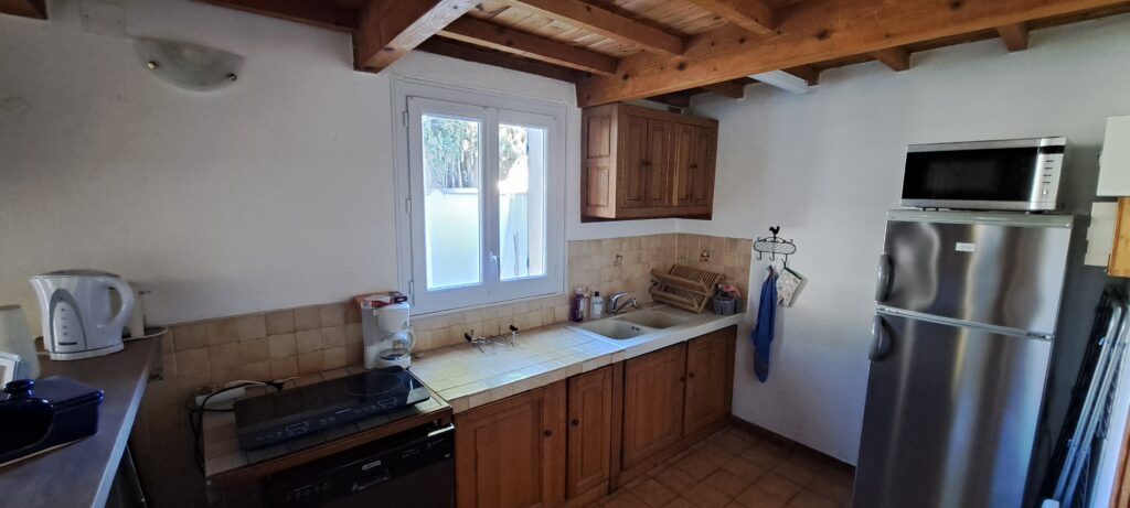 Cuisine équipée de l'Oustau dei Aucèus avec sa fenêtre face à la terrasse et son jardin.