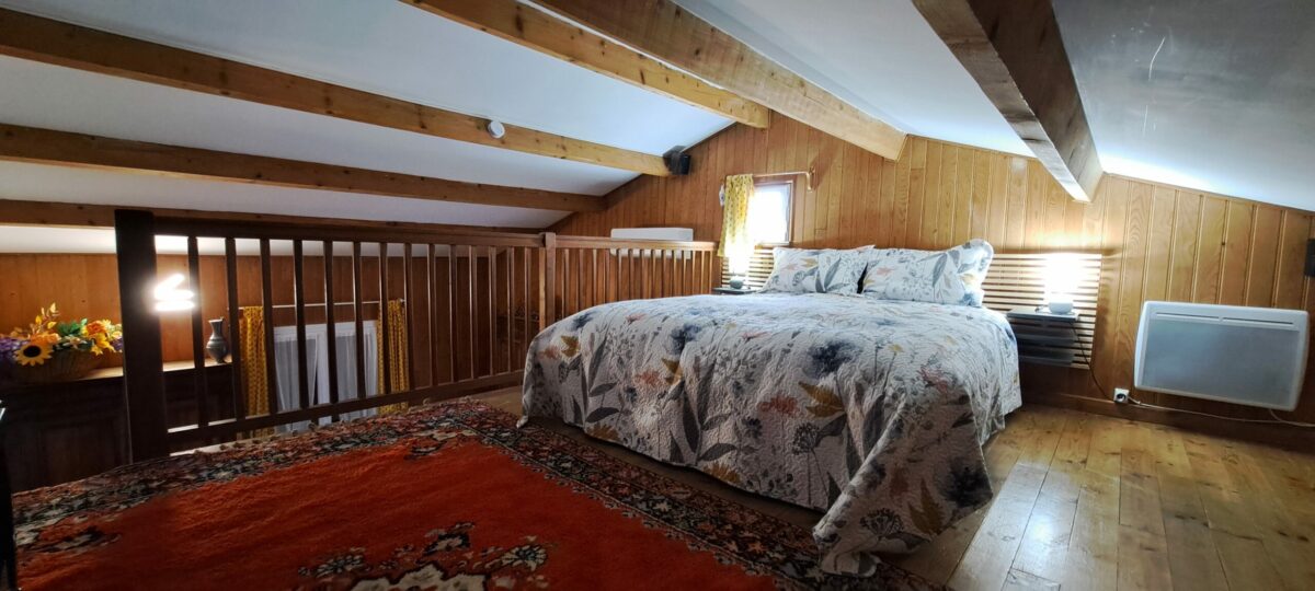 La chambre en mezzanine « Le Nid des Aucèus » avec son lit confortable sous la charpente du duplex, pour un séjour à deux à Saint-Rémy-de-Provence.