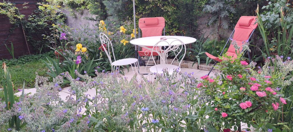 La terrasse privative, close et sans vis-à-vis de L’Oustau dei Aucèus, entourée de roses et de fleurs au printemps 2026 à Saint-Rémy-de-Provence.