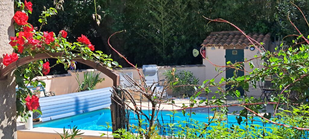 Porte fleurie de roses reliant la terrasse privative à la piscine extérieure partagée de L’Oustau dei Aucèus à Saint-Rémy-de-Provence.