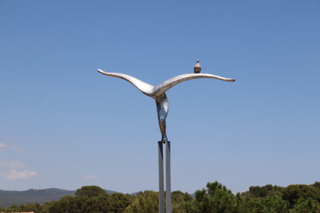 Oiseau posé sur une sculpture représentant l'envol vers d'autres horizon. Image poétique du repos après un voyage de vacances à Saint-Rémy-de-Provence.