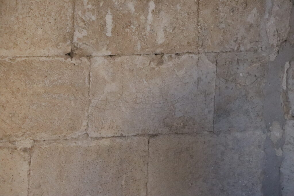 Gravure médiévale représentant un navire, incisée dans la pierre du cloître de l'Abbaye de Montmajour. Une trace étonnante à découvrir lors d'une visite du patrimoine pendant un séjour en Provence.