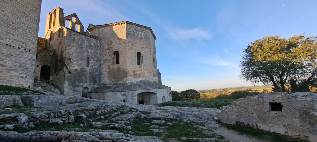 L'Église abbatiale Notre-Dame de l'Abbaye de Montmajour, vue extérieur sur la crypte Saint-Benoît avec des vestiges au premier plan et la plaine environnante. Une découverte du patrimoine à faire lors d'une promenade depuis L'Oustau dei Aucèus à Saint-Rémy-de-Provence.