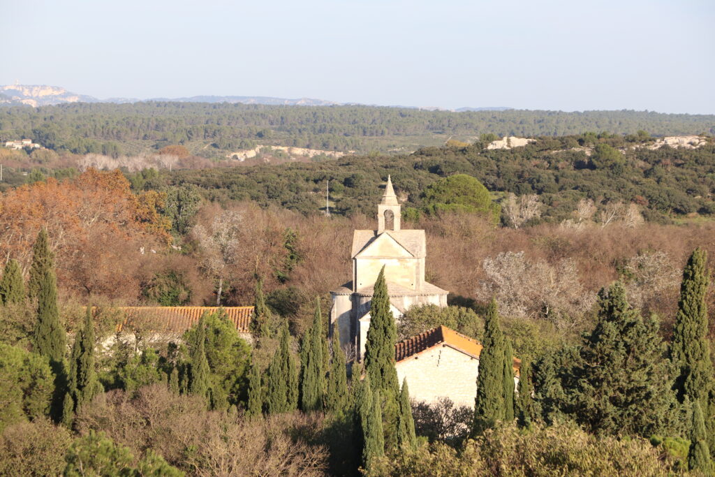 Chapelle Sainte-Croix de l’Abbaye de Montmajour, construite au XIIe siècle à 200 mètres à l’extérieur de l’abbaye pour accueillir les pèlerins, dans la plaine du pays d’Arles, avec le plateau de la Caume, point culminant des Alpilles à Saint-Rémy-de-Provence, à l’horizon.