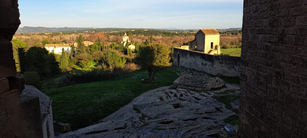 La nécropole rupestre au Levant de l'Abbaye de Montmajour, située au pied de la crypte Saint-Benoît, avec la chapelle Sainte-Croix qui était la destination du pèlerinage religieux « le Pardon de Montmajour », puis la plaine jusqu'au massif des Alpilles à l'horizon.